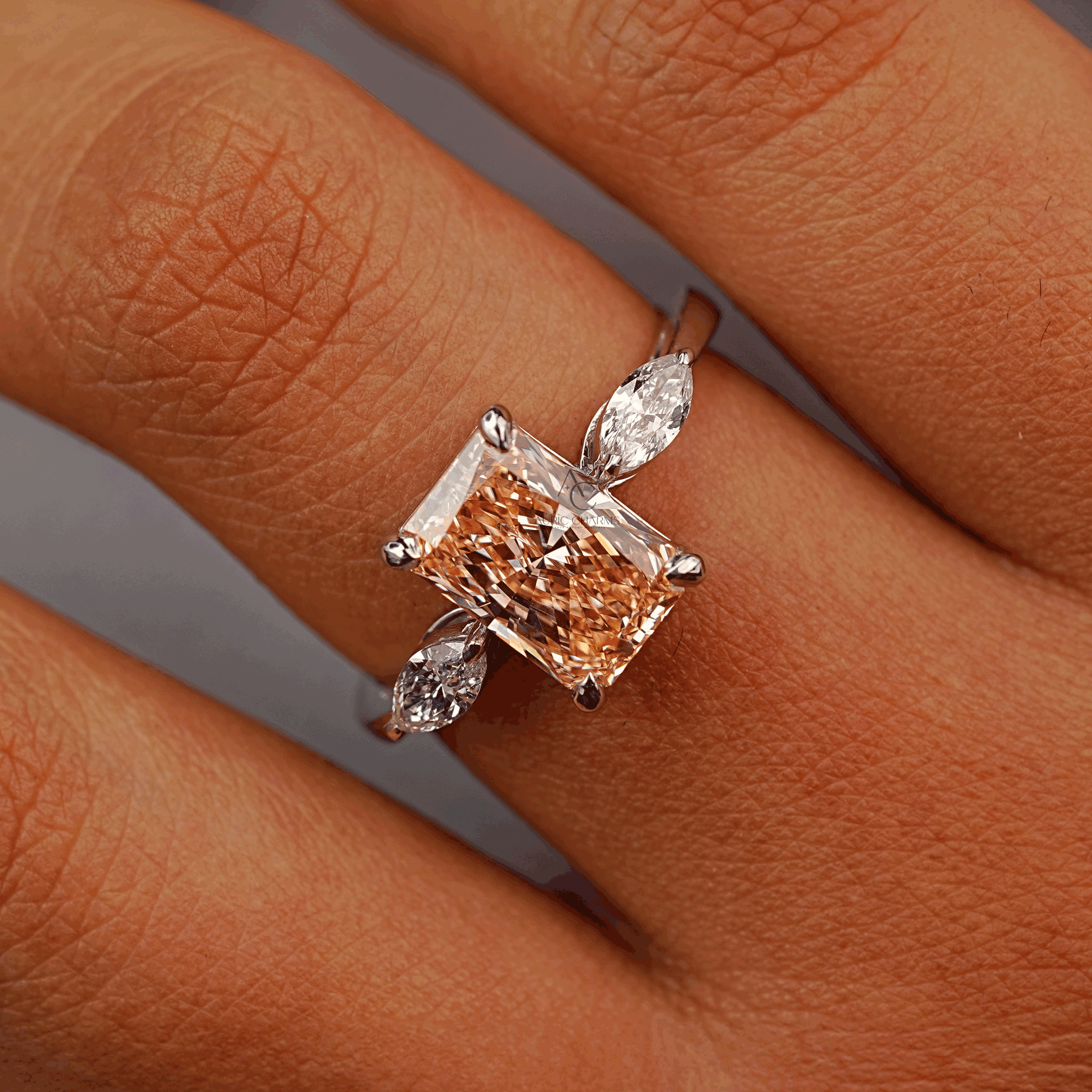Hand-shot of a radiant-cut champagne lab-grown diamond engagement ring with marquise side stones, set on a polished white gold band