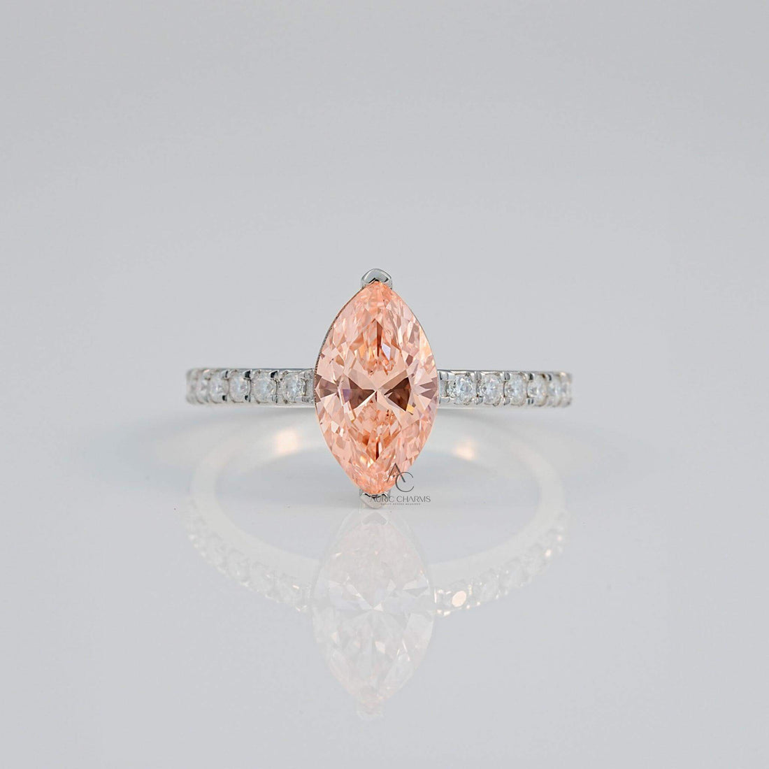 Close-up of a marquise pink gem with a diamond-studded silver band reflecting light.