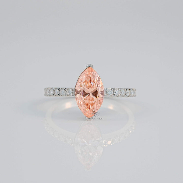Close-up of a marquise pink gem with a diamond-studded silver band reflecting light.