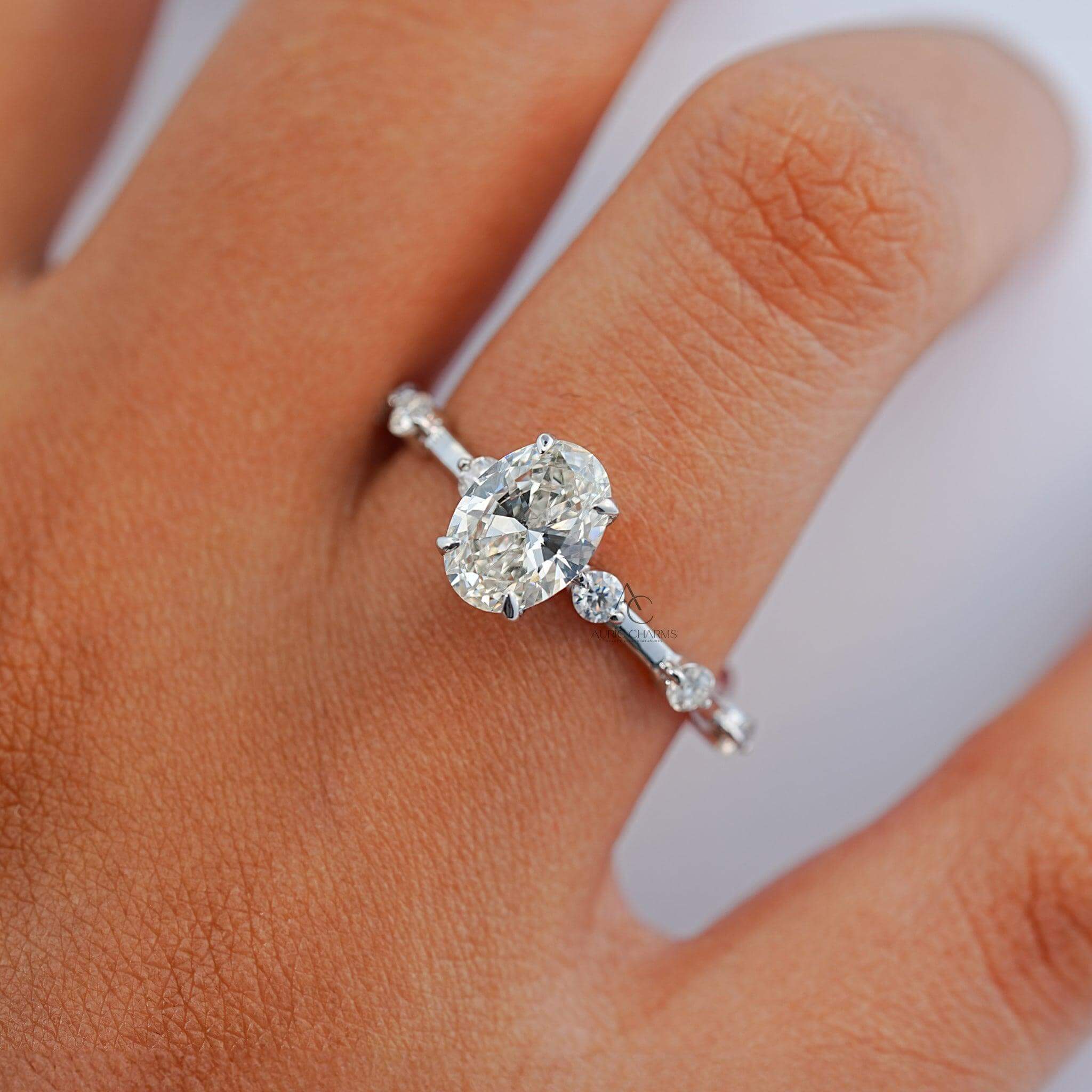 Handshot of an oval diamond ring featuring a shimmering stone and a diamond-accented band, highlighting its luxurious design in real-life perspective.