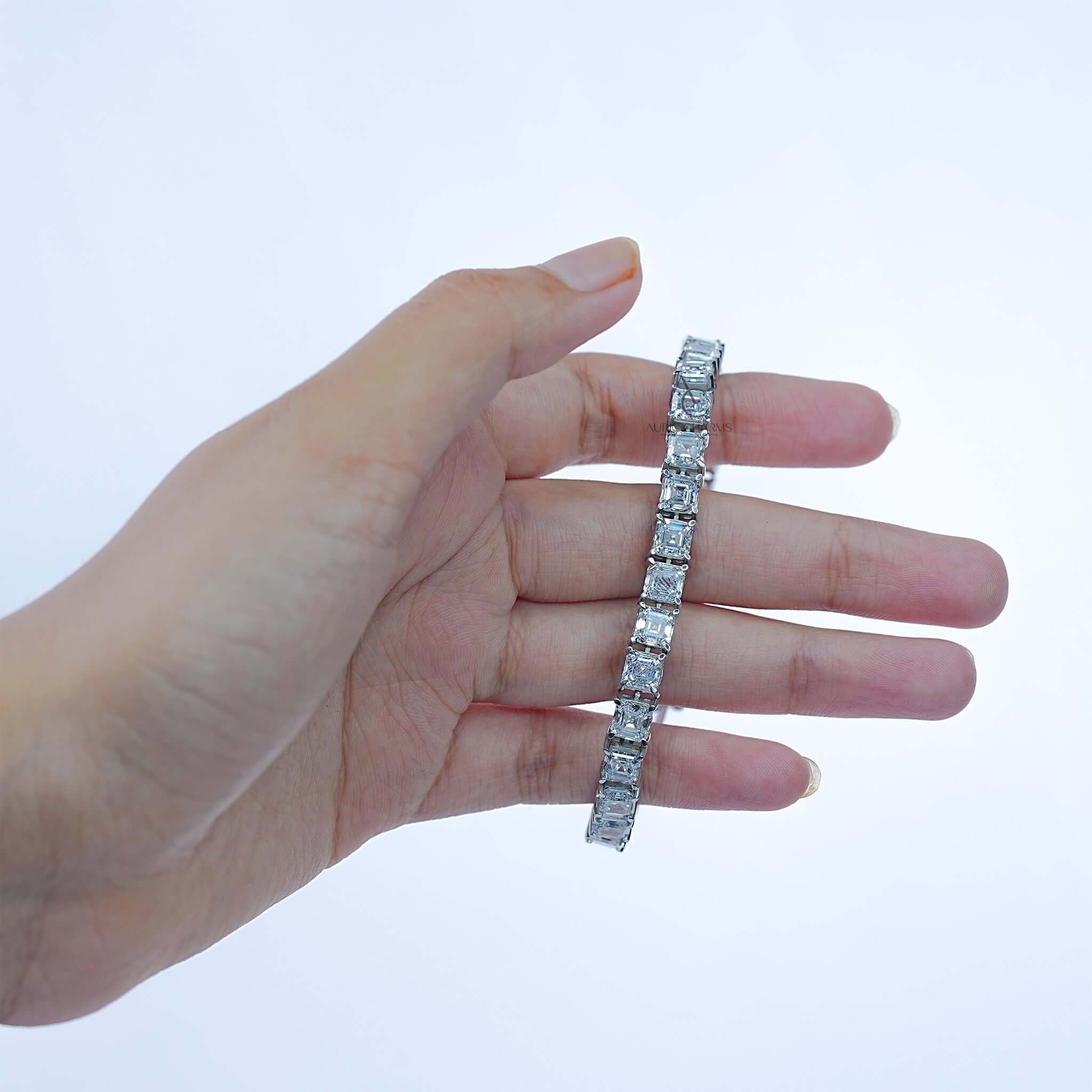 Hand holding white gold bracelet with princess-cut lab-grown diamonds for detail view.