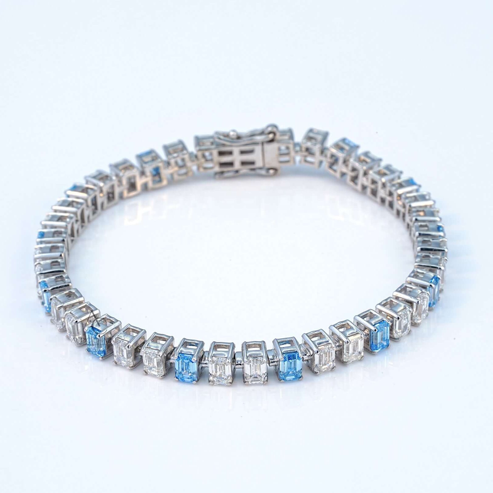 Top view of white gold bracelet featuring lab-grown diamonds and blue sapphires in emerald cut.