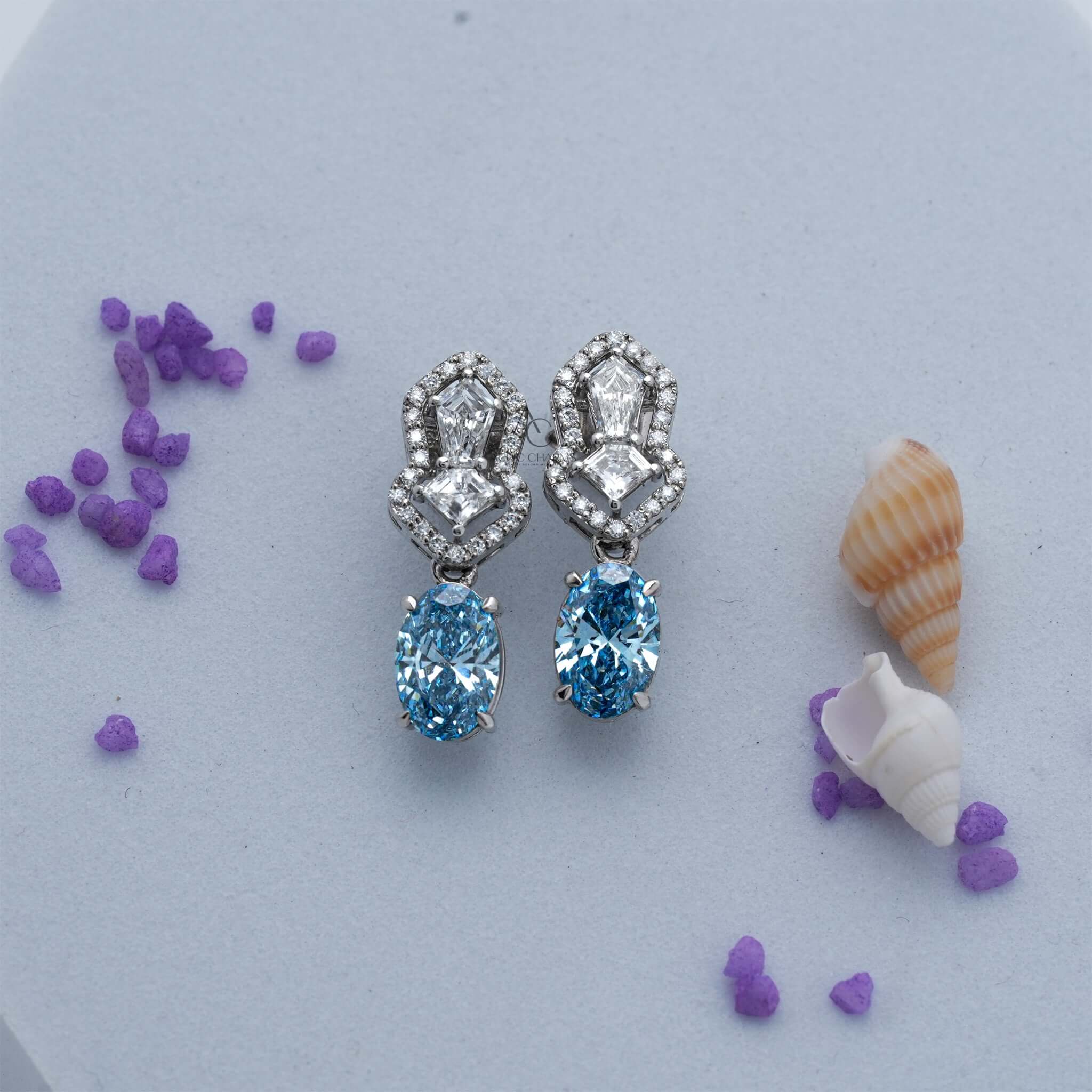 Diamond and blue gemstone drop earrings with intricate design and oval cut stones.
