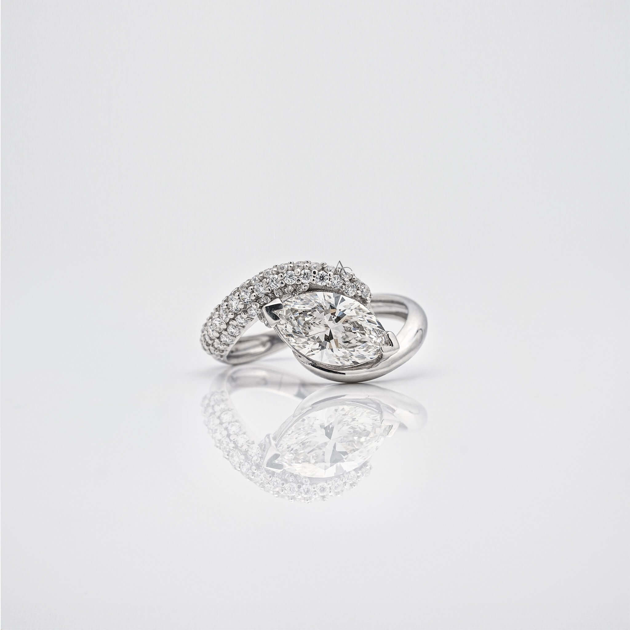 Diamond ring with pear-shaped center stone and curved diamond-encrusted band.