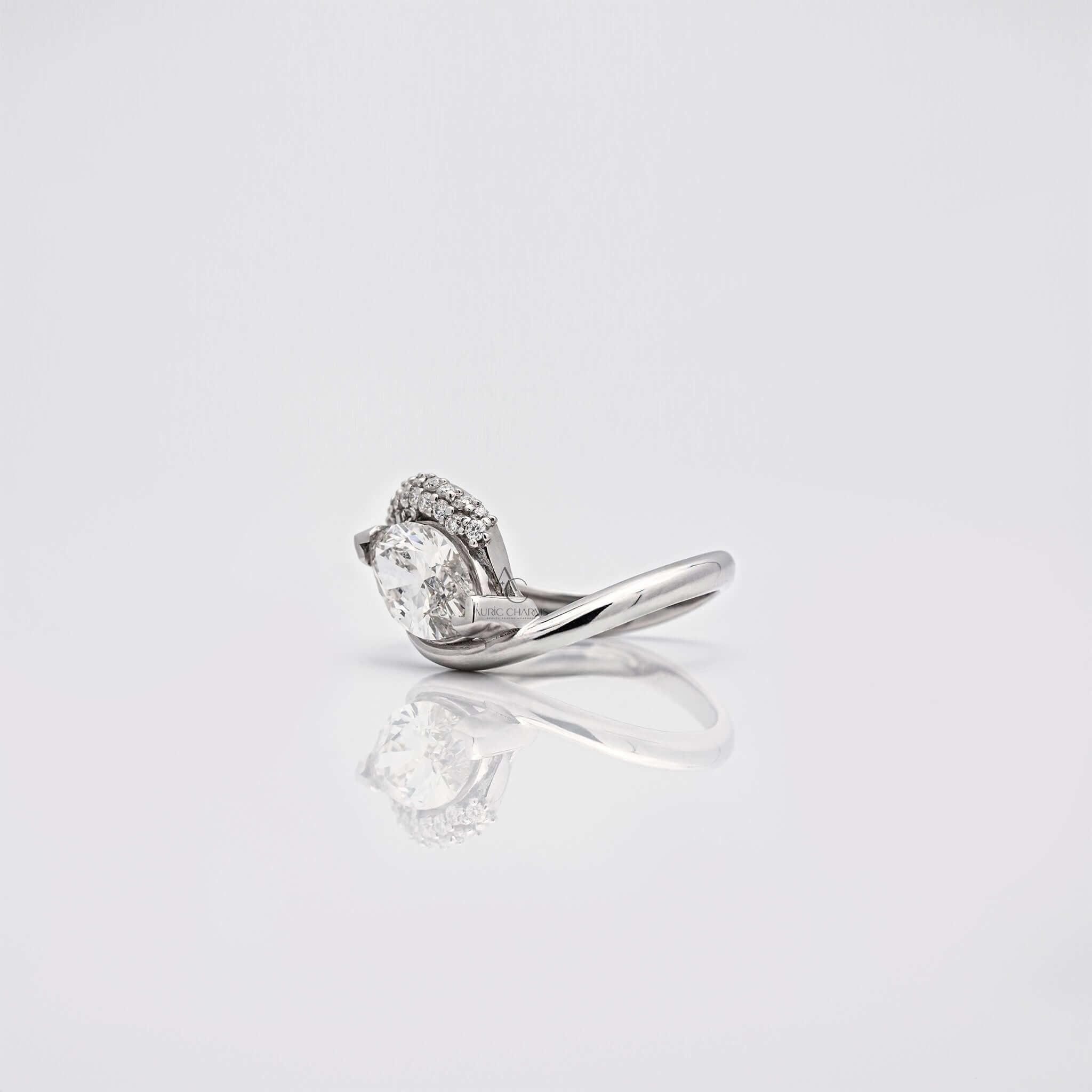 Side view of pear-shaped diamond ring with curved band and side stones.