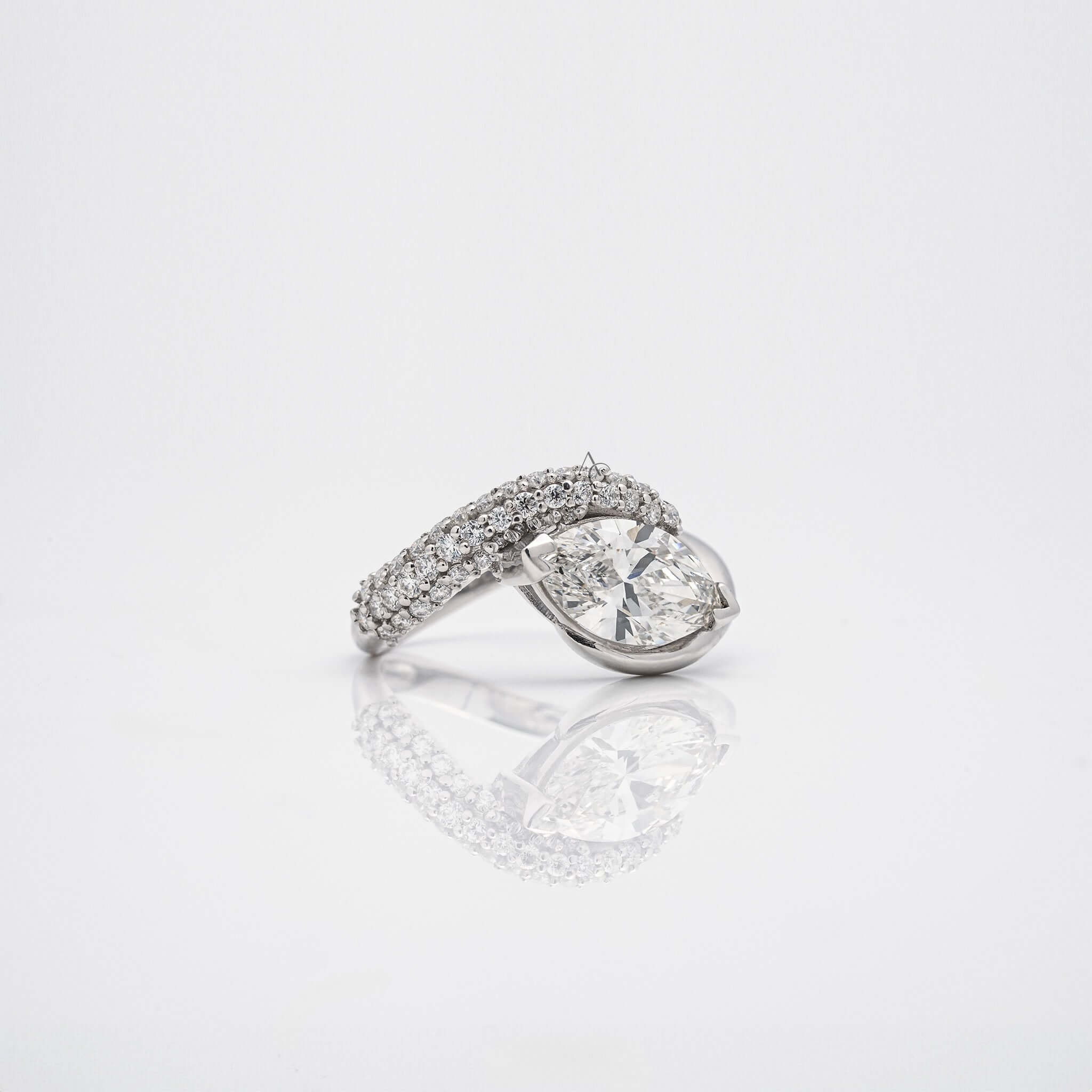 Angled view of pear diamond ring with diamond-accented band on white background.