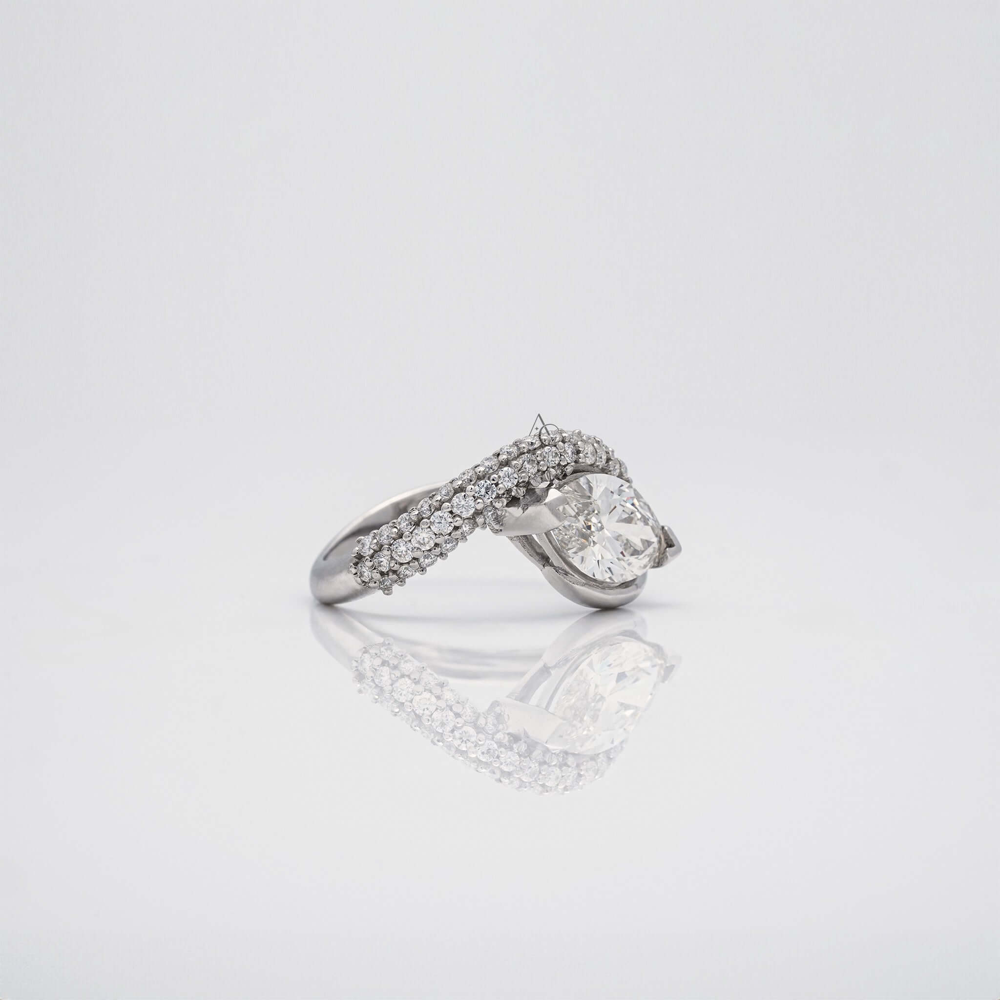 Side-facing pear-shaped diamond ring with a pave diamond band on white.
