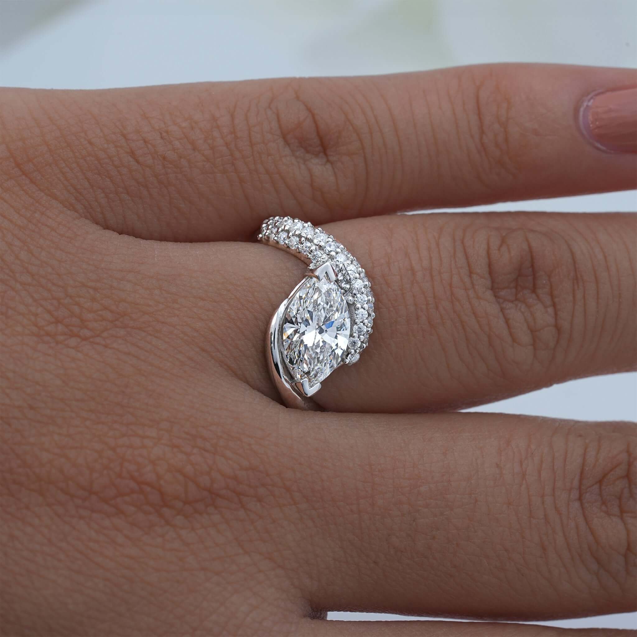 Hand wearing pear diamond ring with curved diamond pave band.