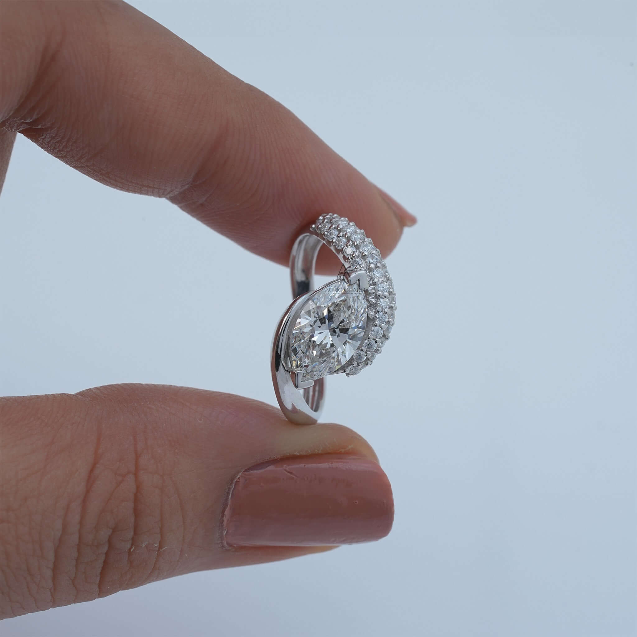 Pear-shaped diamond ring held between fingers, showcasing band details.