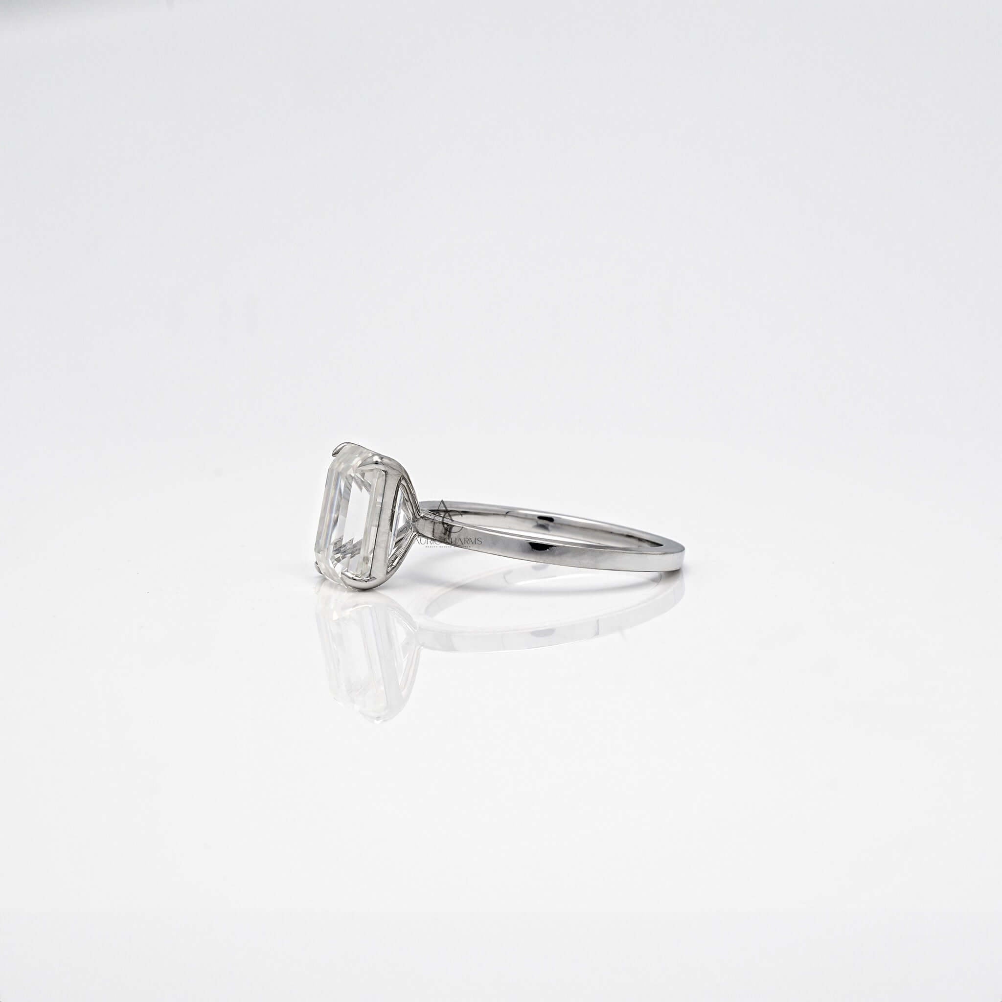 Profile view of emerald diamond ring with thin band.