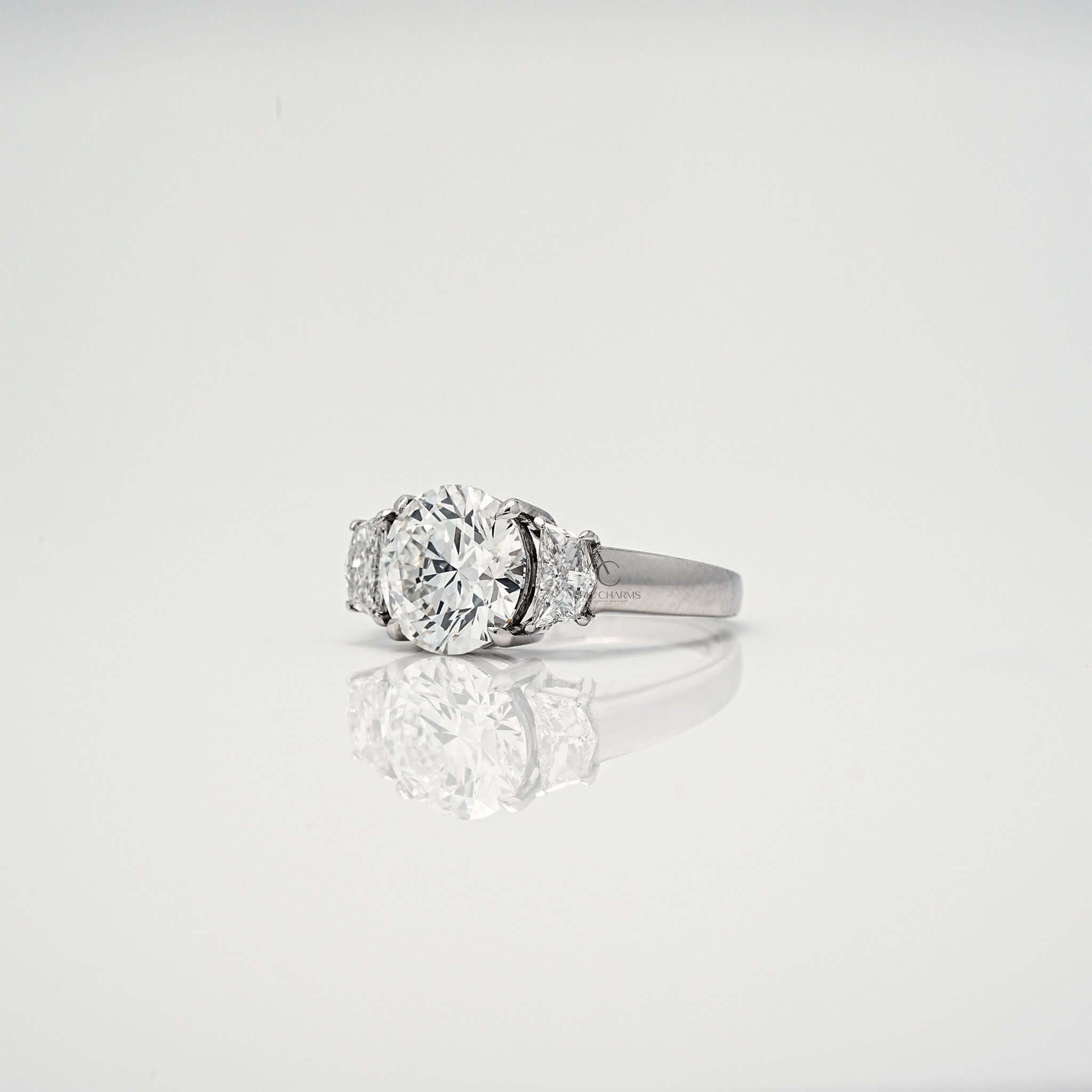 Side view of round brilliant diamond ring with tapered side stones.