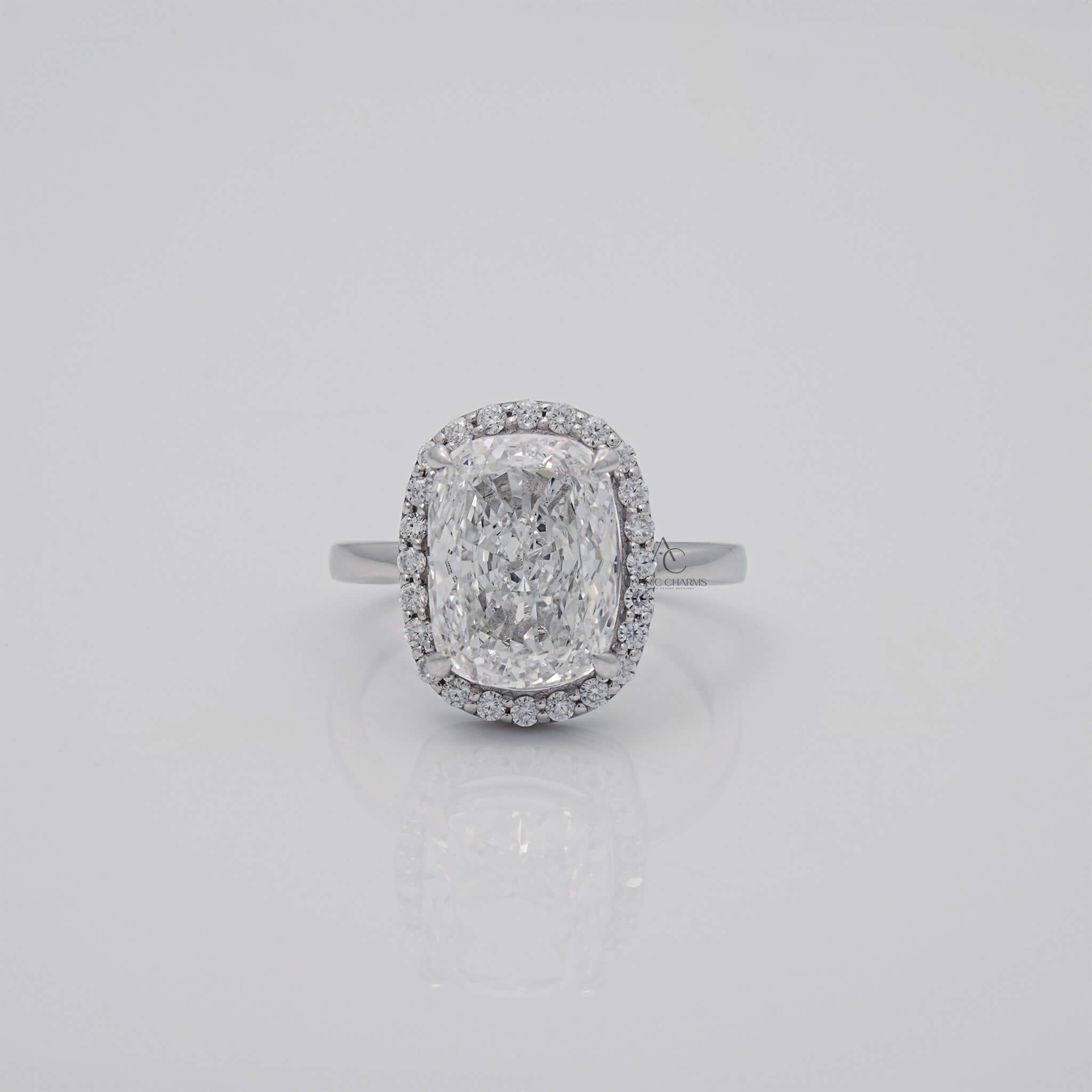 Cushion-cut diamond ring with halo on reflective surface.
