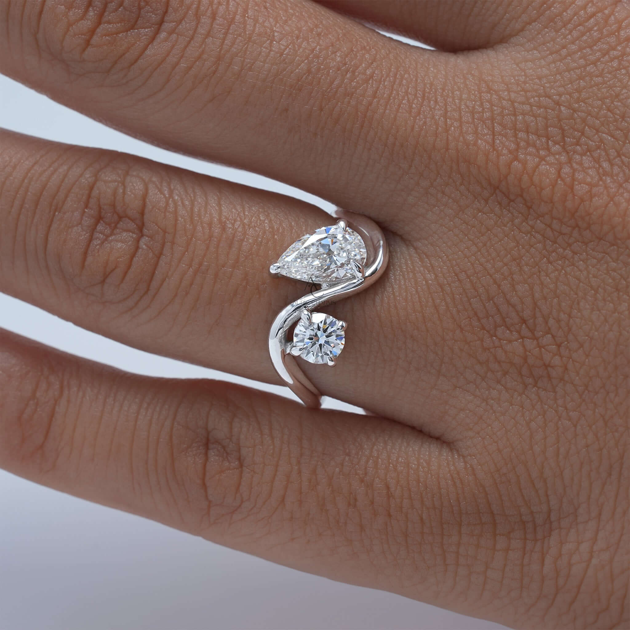 Bypass ring with pear and round diamonds on hand.