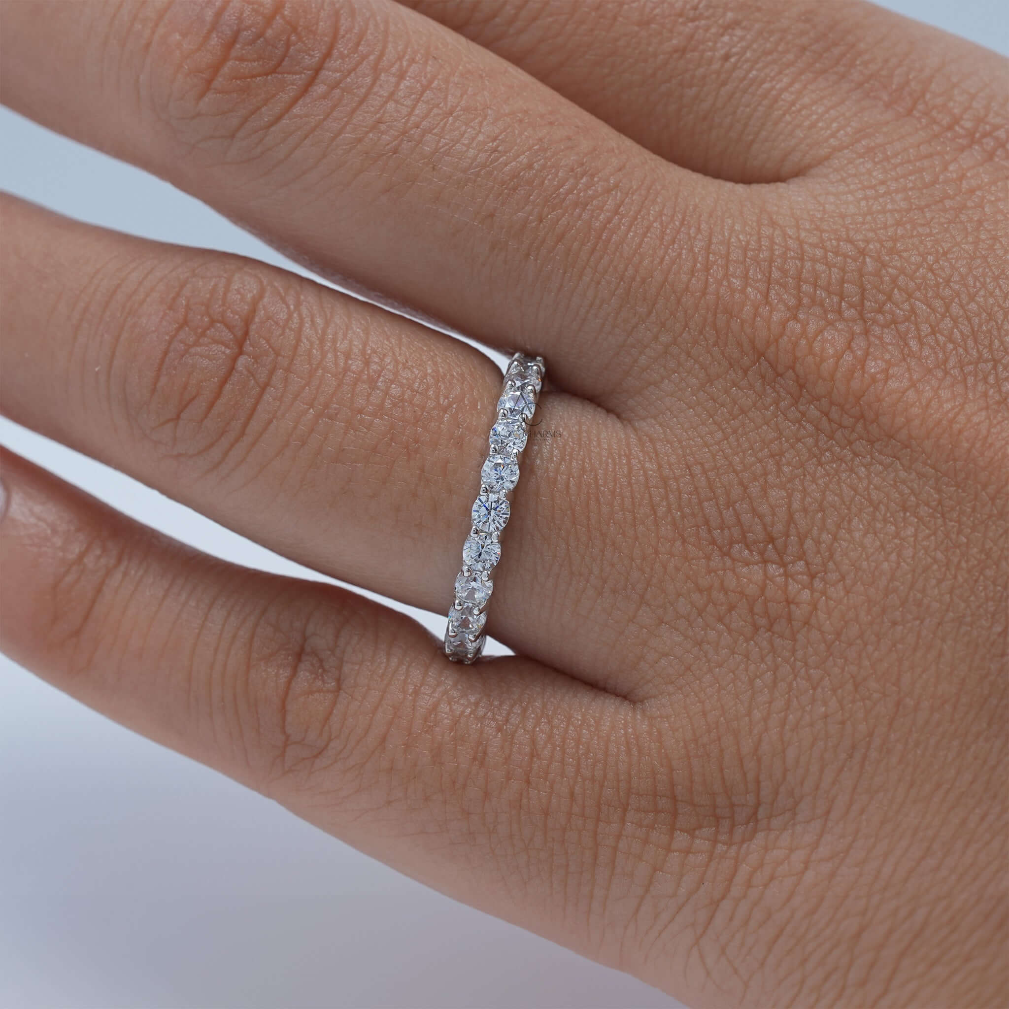 Diamond eternity band worn on hand, showcasing its brilliant round diamonds.