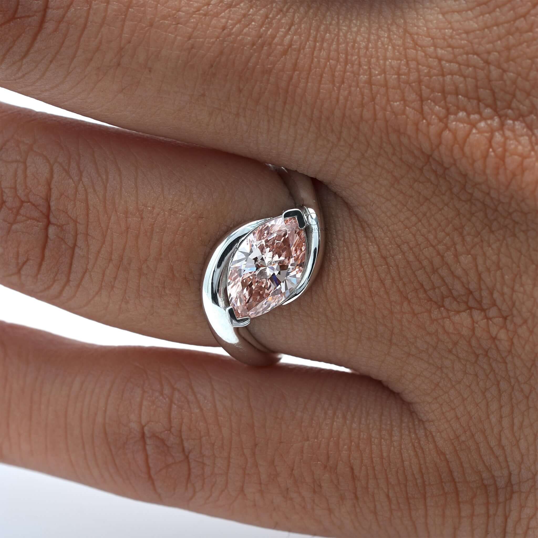 Marquise pink diamond ring on finger with elegant bypass band design.