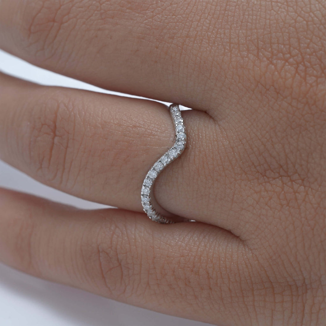 Wavy diamond ring on finger, elegant and modern design.