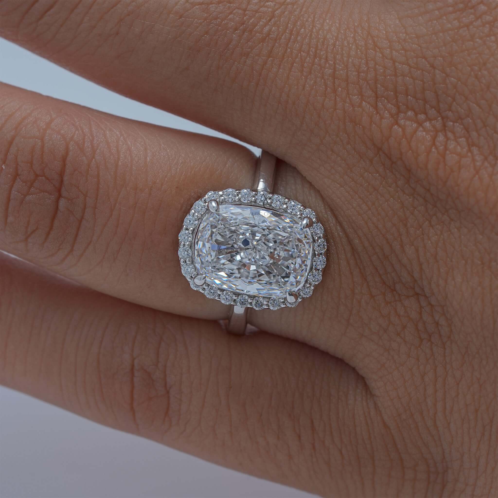 Cushion-cut diamond halo ring worn on finger.