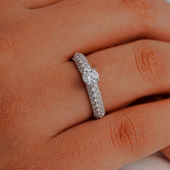 A hand model wearing a round-cut diamond pavé ring, highlighting the brilliance and sparkle of the ethically sourced diamonds.