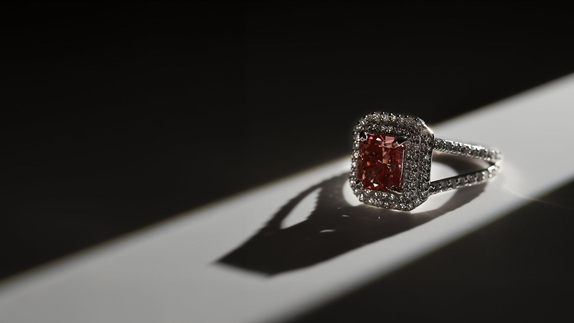 Ring with a red gemstone and diamond-studded band on a dark background