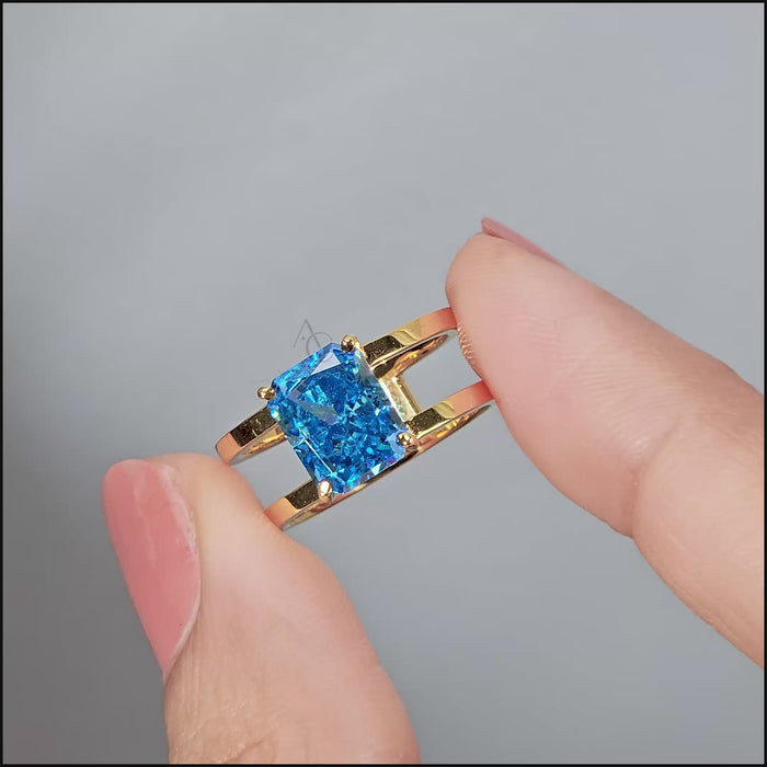 A gold ring with a rectangular-cut bright blue gemstone placed