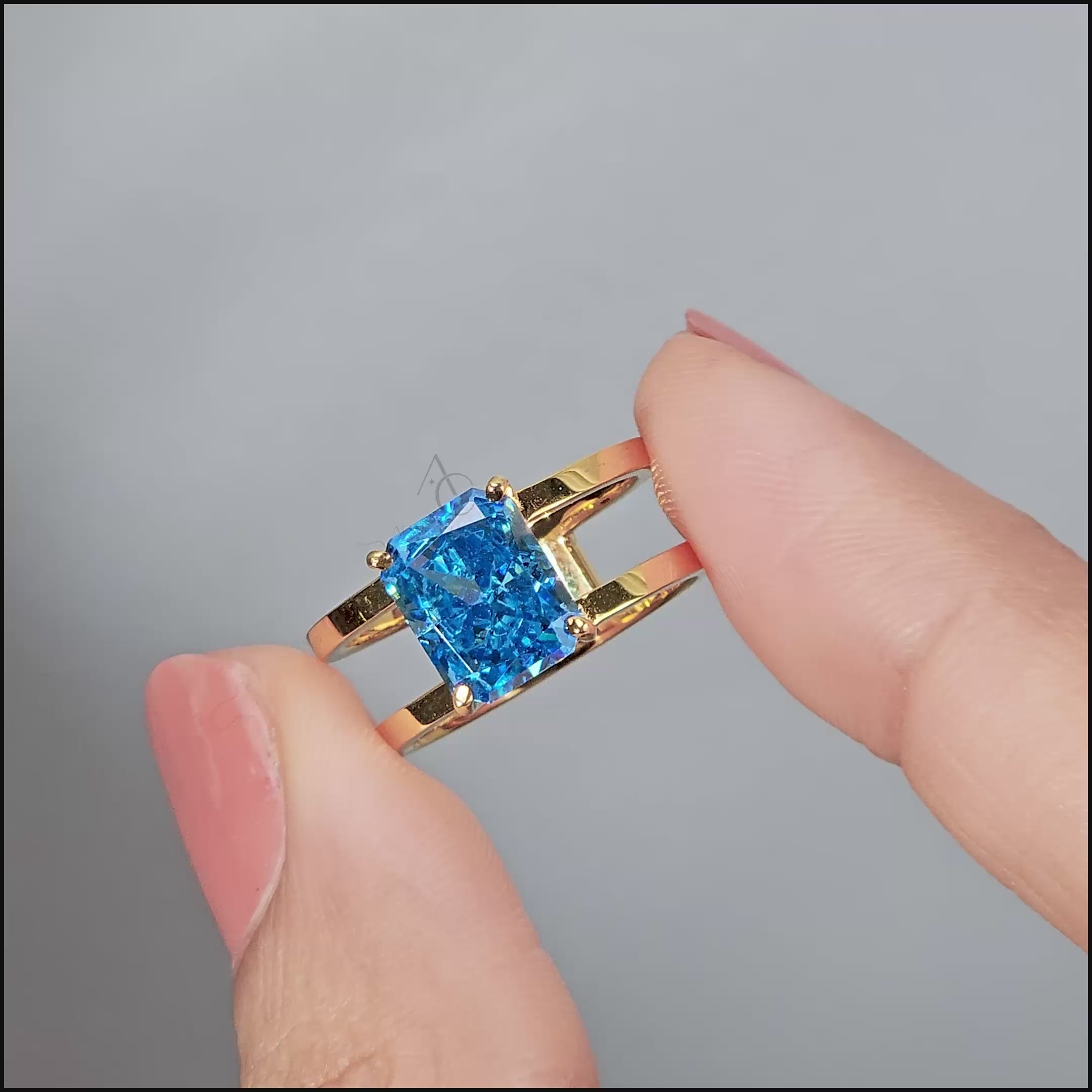 A gold ring with a rectangular-cut bright blue gemstone placed