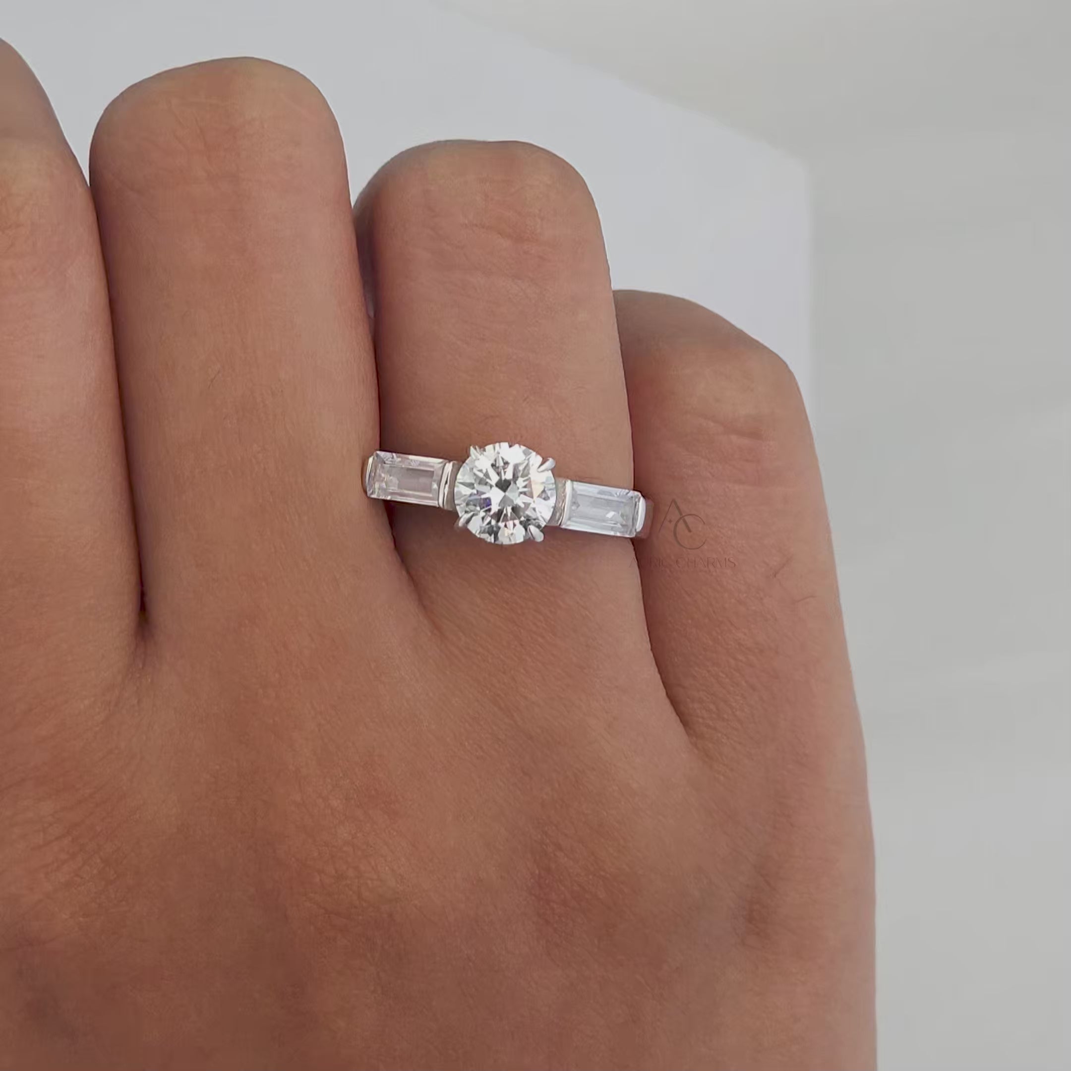 A stunning showcase of a round-cut diamond engagement ring with baguette side stones in platinum, featuring 360-degree views to highlight its radiant sparkle and craftsmanship.