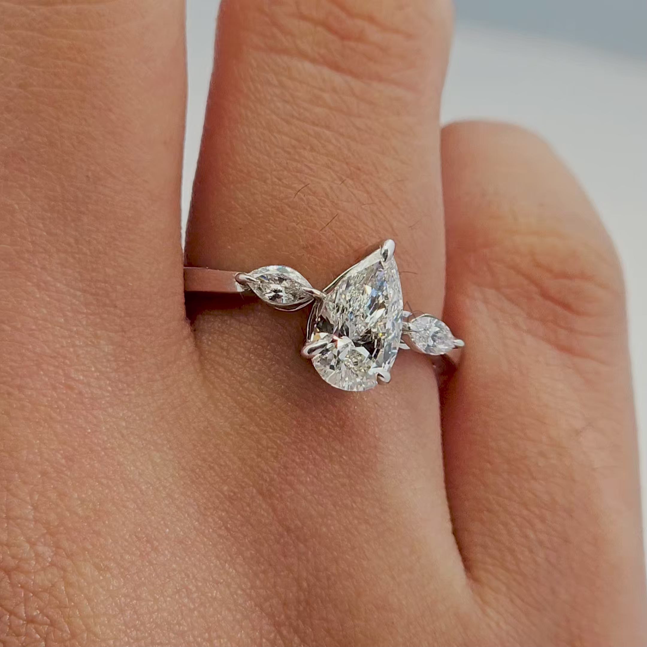 360-degree view of a pear-cut diamond ring with marquise side stones.