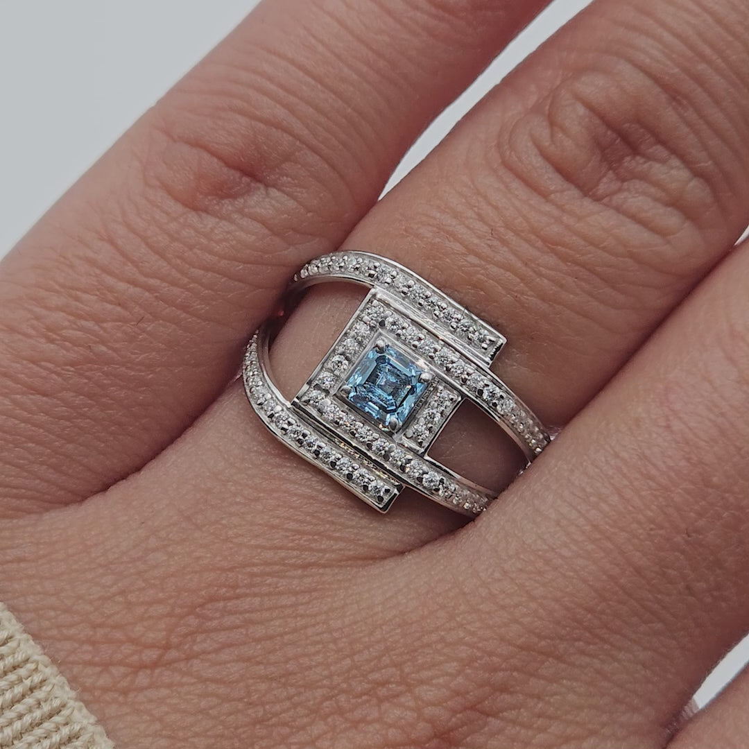 Rotating view of square blue gemstone ring with diamond halo and split double band.