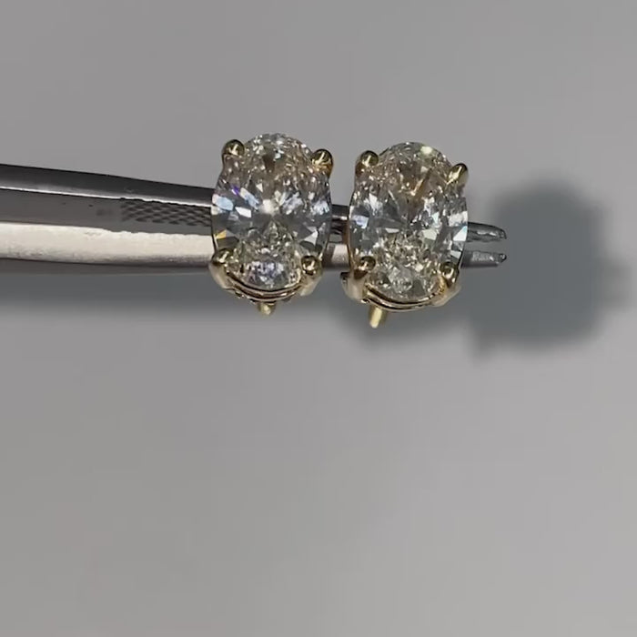 Rotating oval diamond stud earrings showing clarity and white gold prong setting.