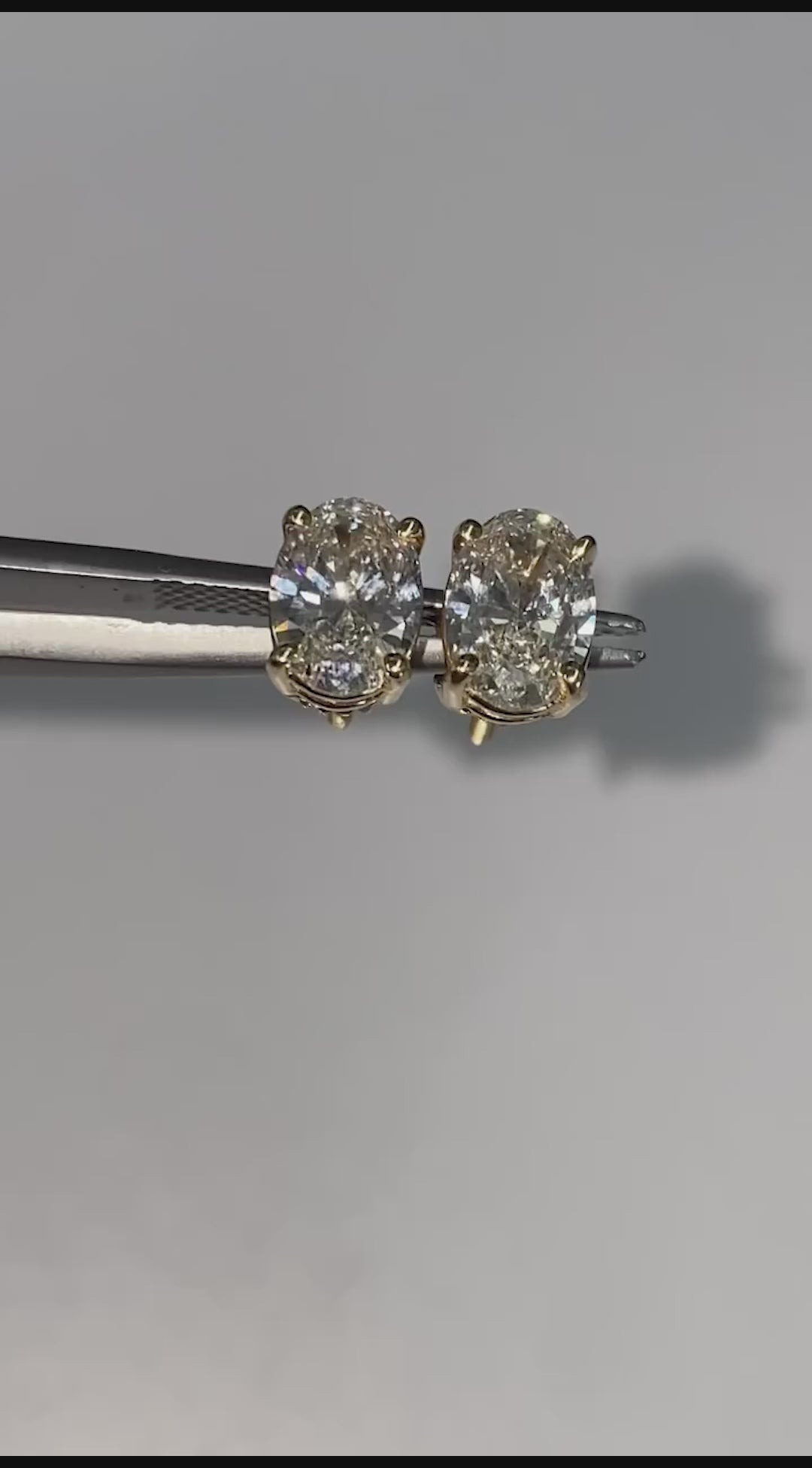 Rotating oval diamond stud earrings showing clarity and white gold prong setting.