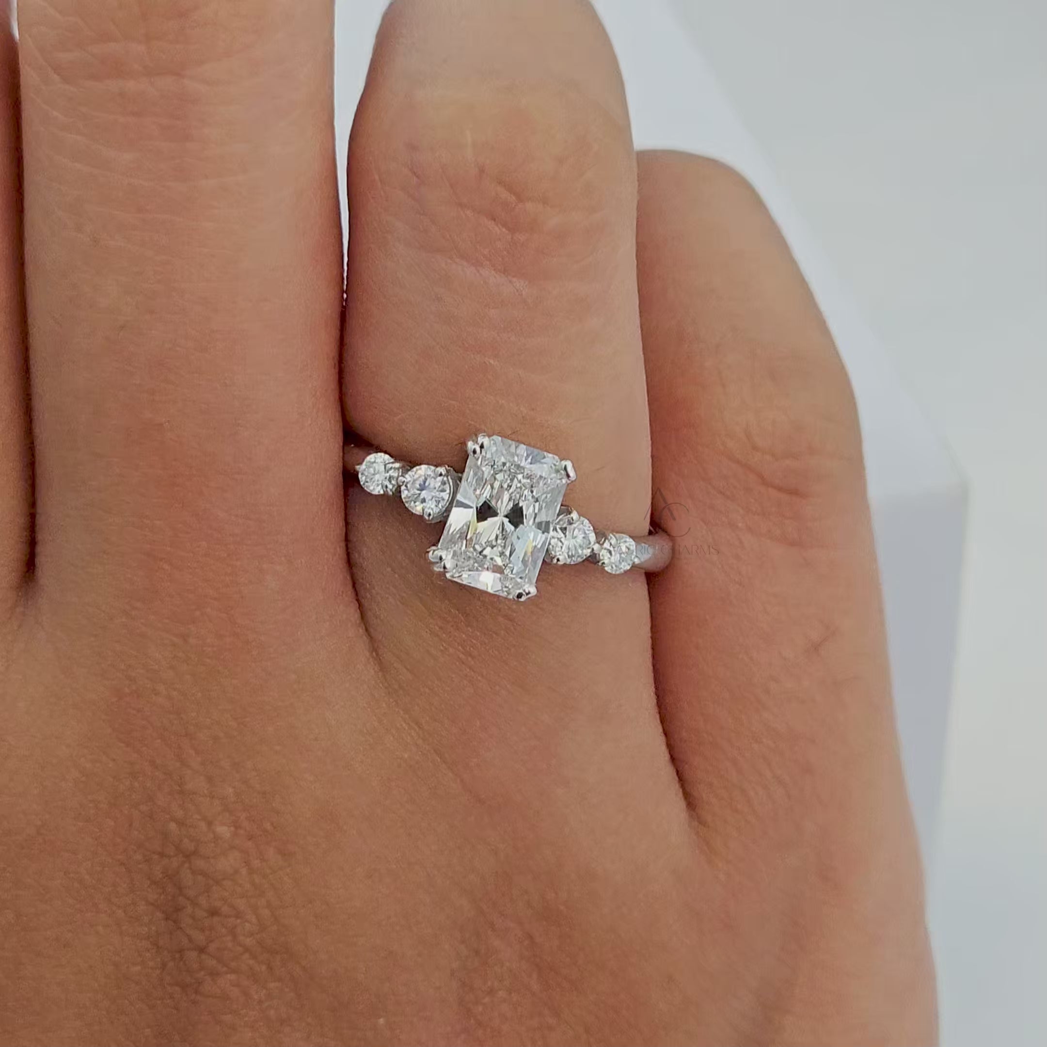 360° view of a radiant-cut diamond engagement ring with side stones in white gold.