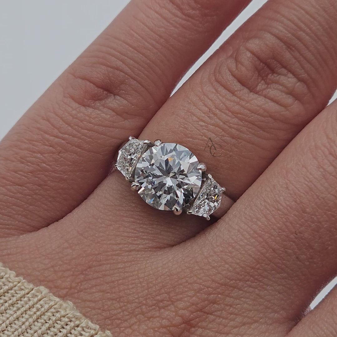 Round brilliant diamond ring with side stones rotating to show details.