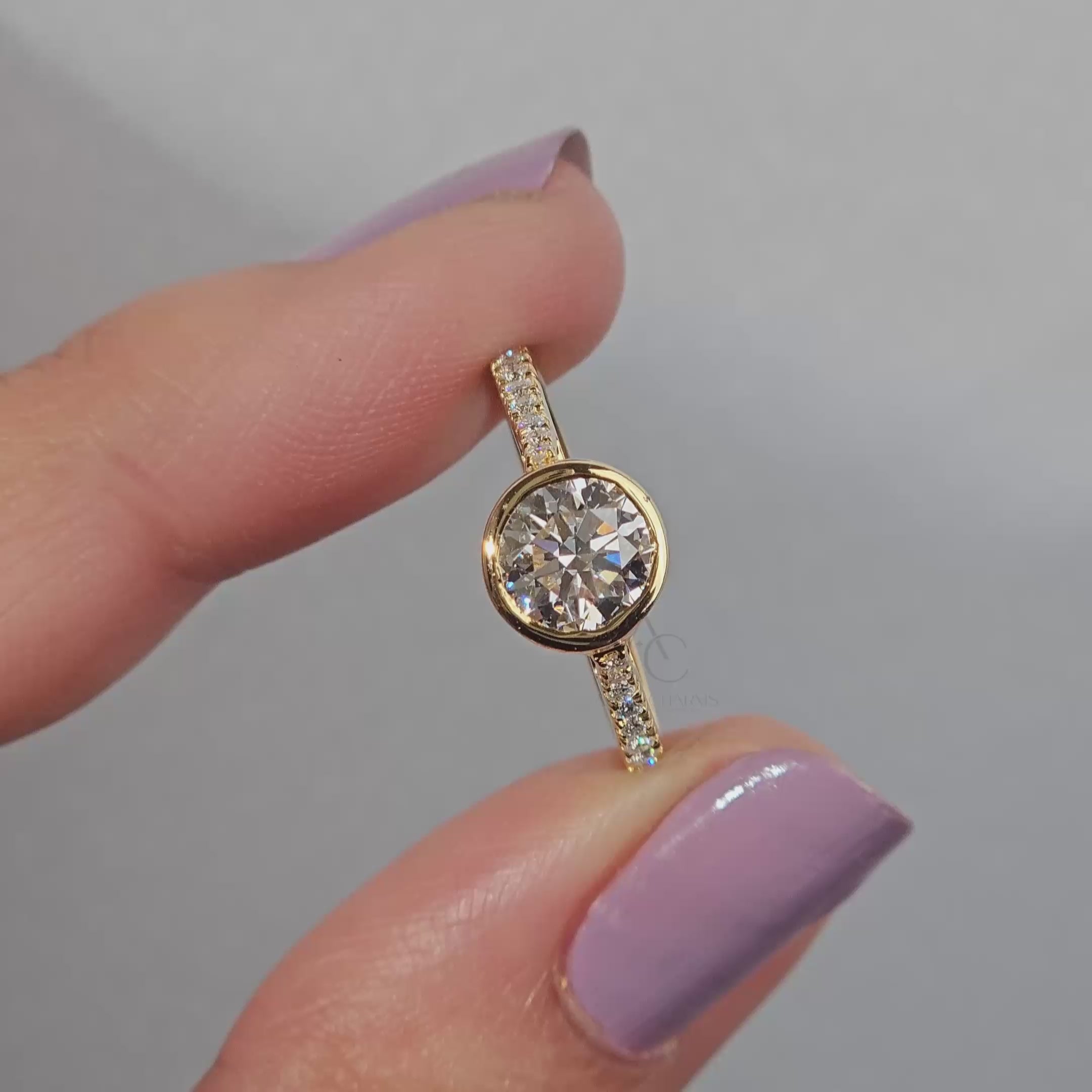 Close-up of a bezel-set diamond ring on a reflective surface.