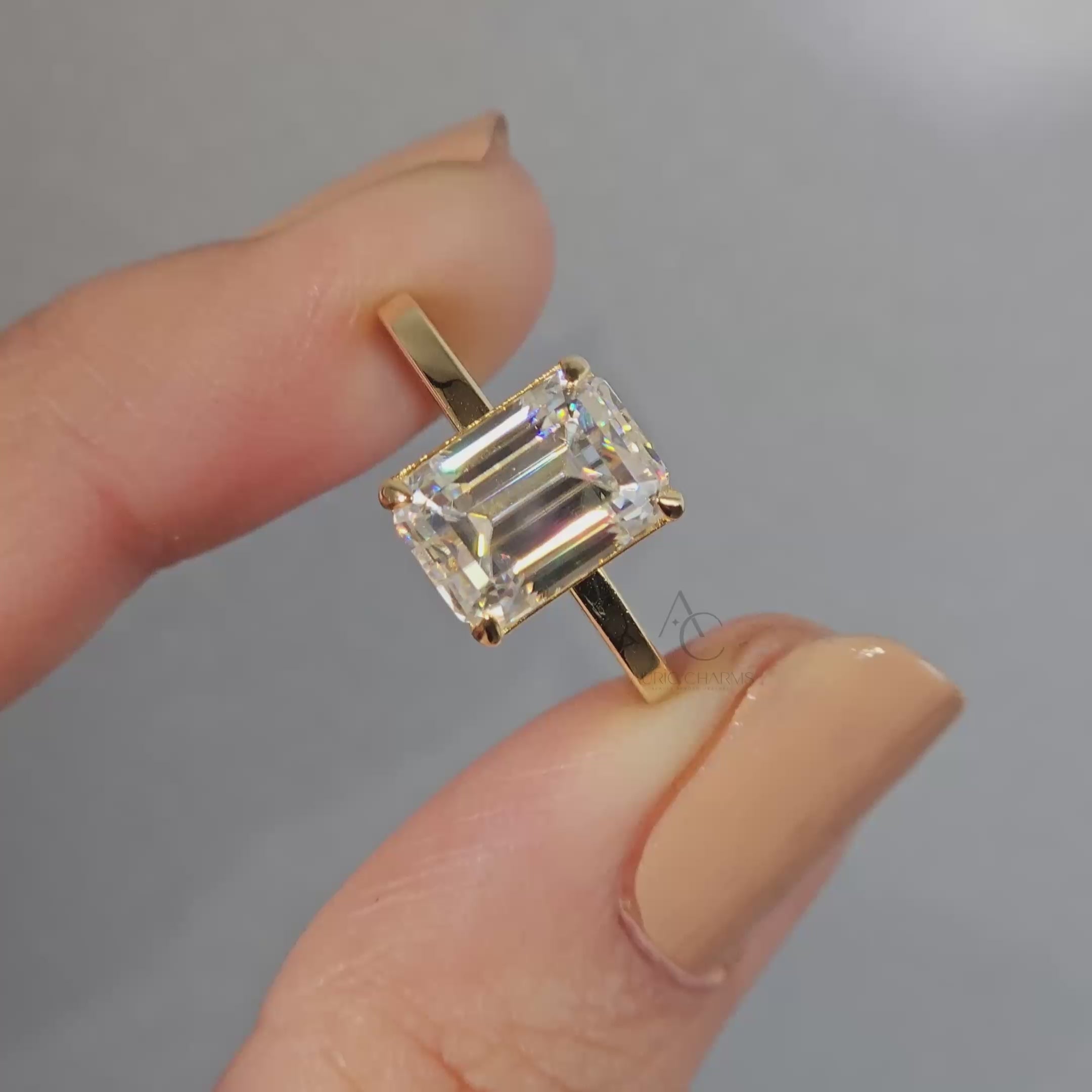 Emerald-cut diamond solitaire ring with sleek band rotating to show all angles.