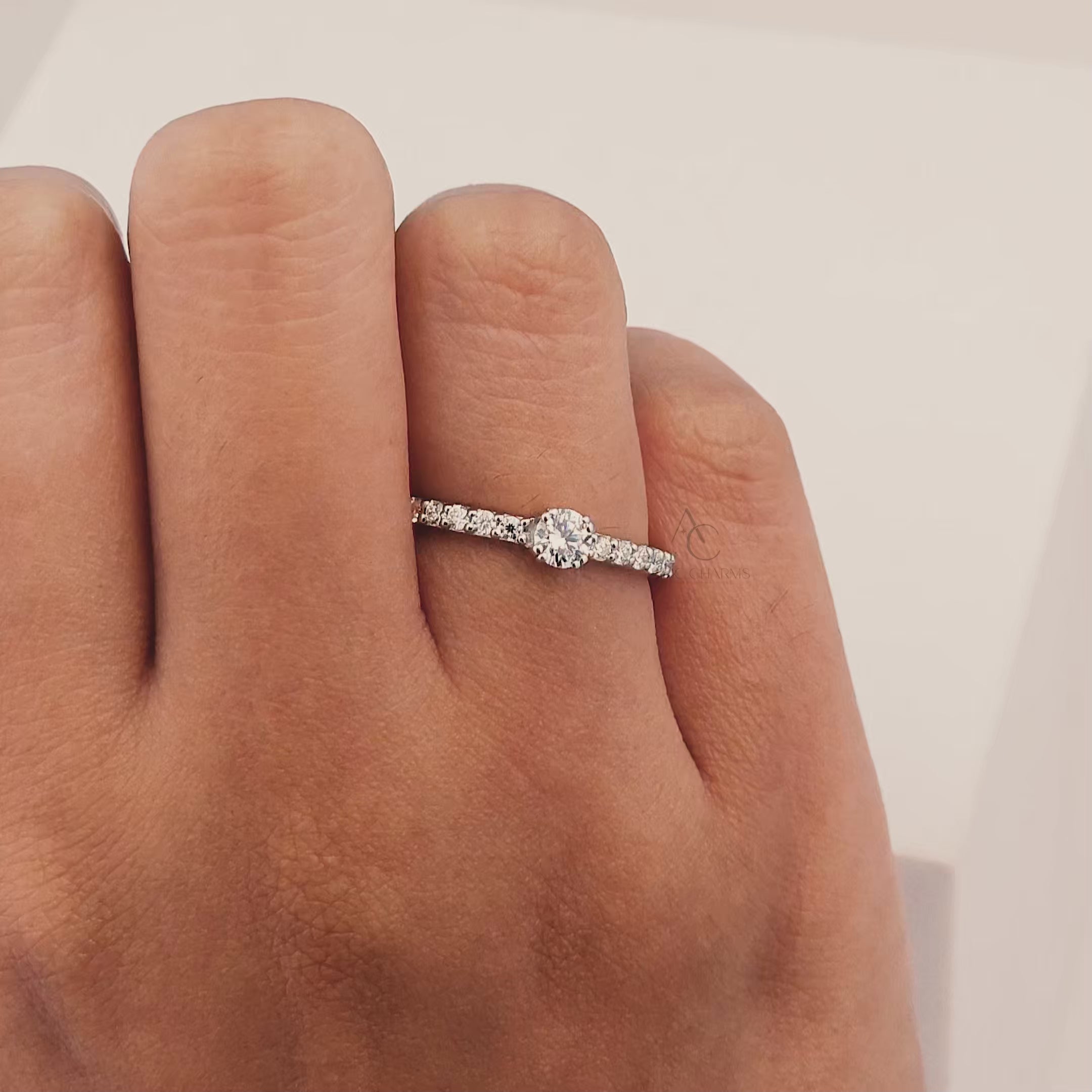 A stunning close-up video showcasing a round-cut diamond solitaire engagement ring with a pave band, highlighting its brilliance from multiple angles.
