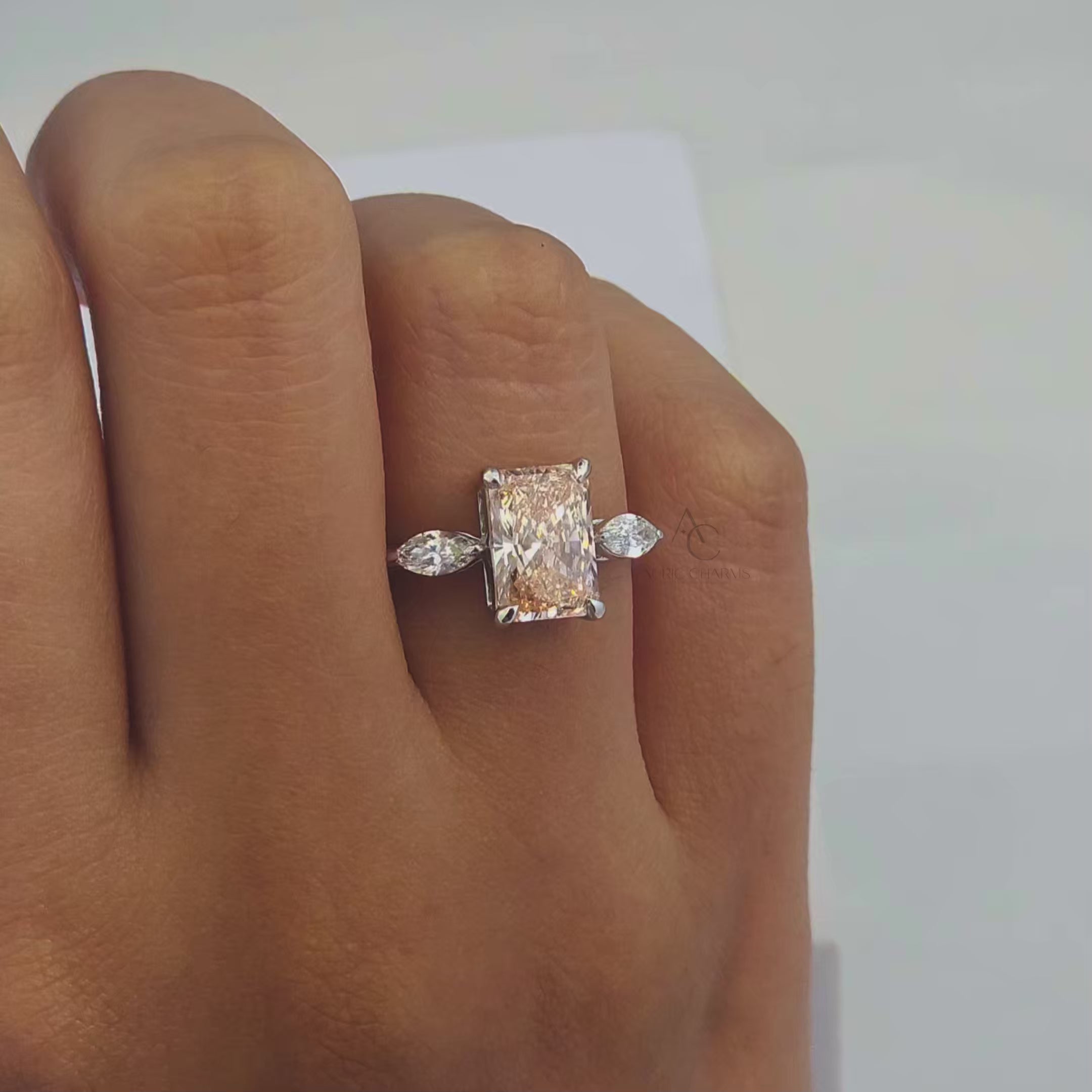 360-degree view of a radiant-cut champagne-colored lab-grown diamond engagement ring with marquise side stones in a sustainable white gold setting.