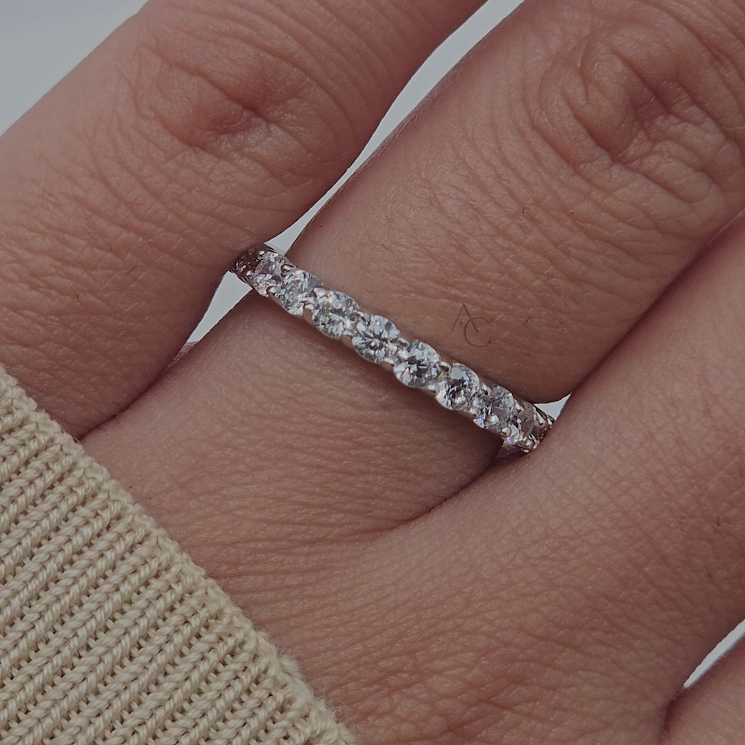 Close-up rotation of a diamond eternity band, highlighting round diamonds and white gold.