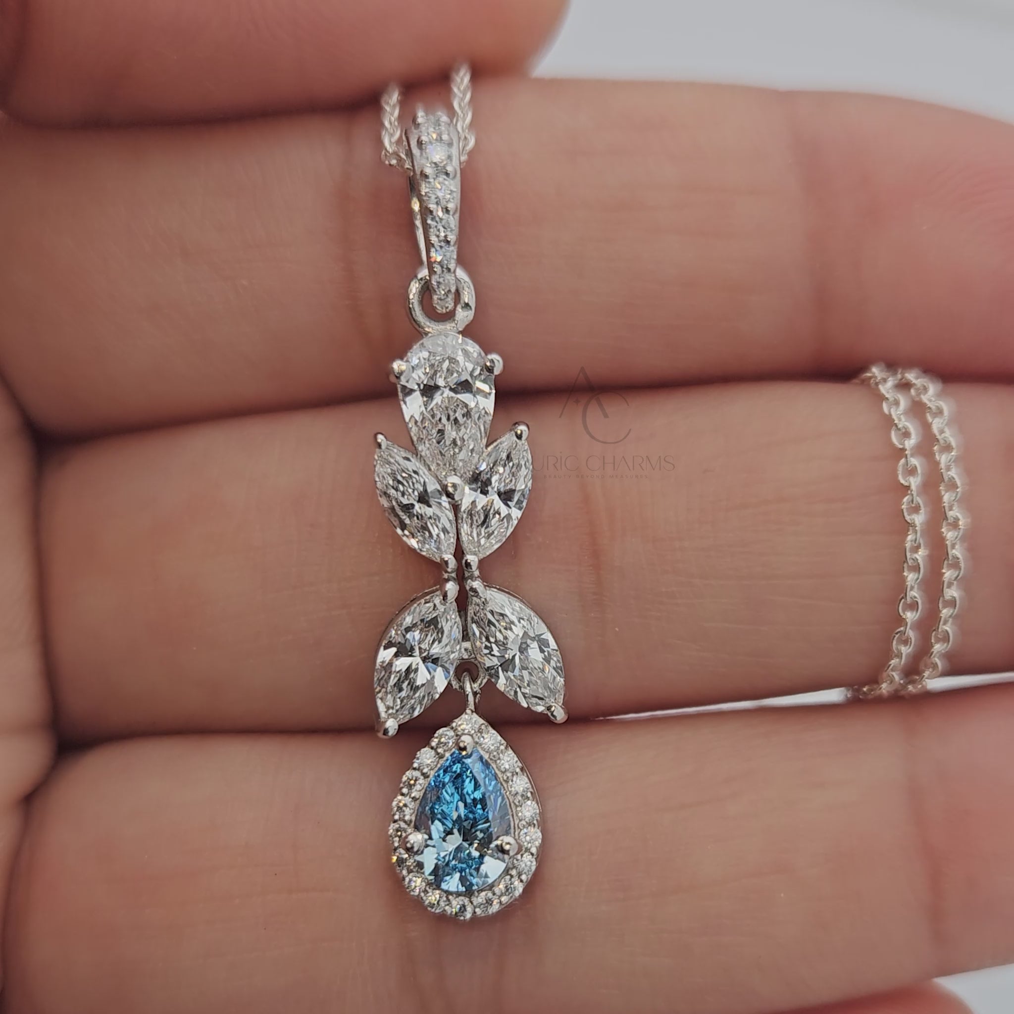360-degree view of white gold pendant with lab-grown diamonds and blue sapphire drop.