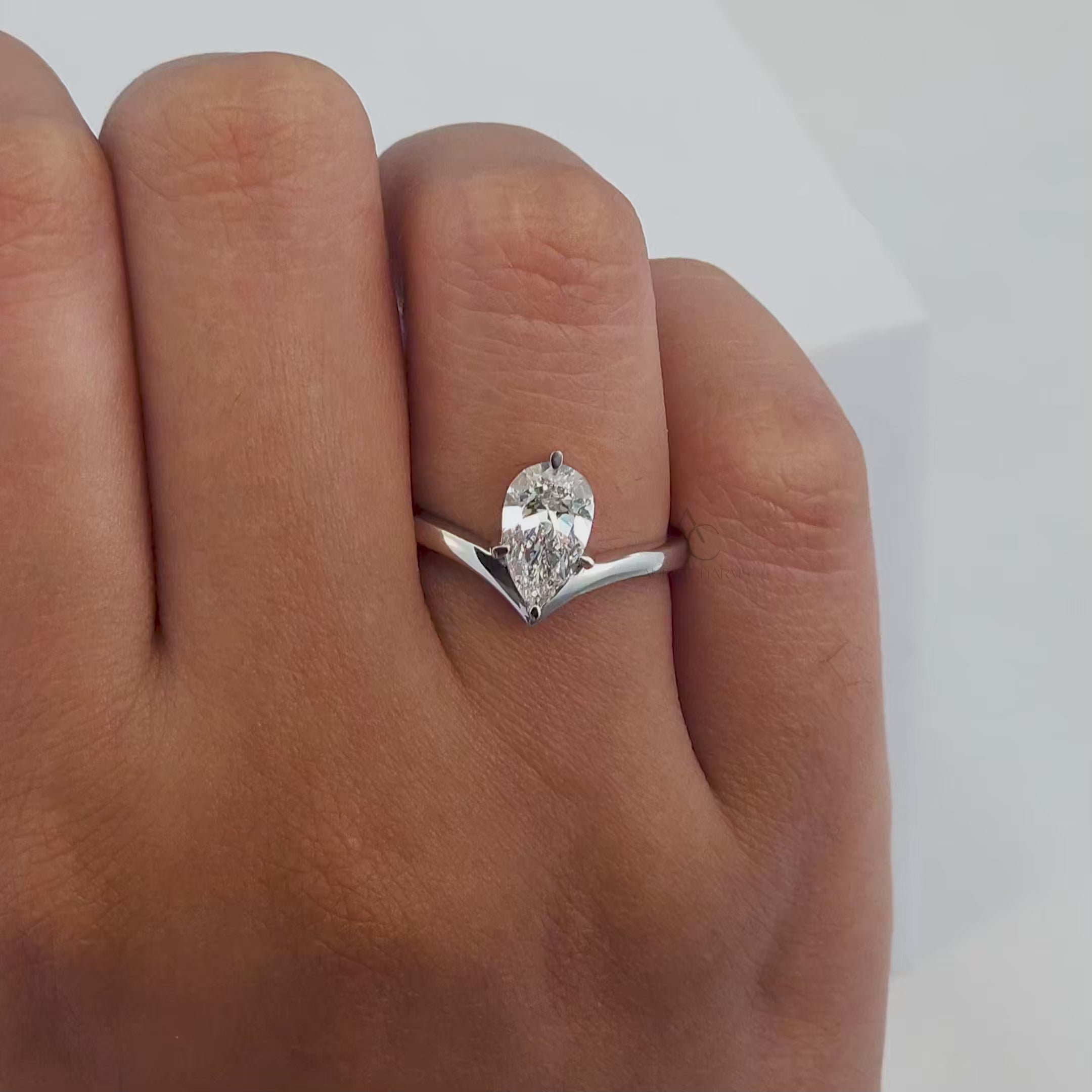 A 360-degree view of a pear-cut diamond engagement ring with a sleek V-shaped band, showcasing its brilliance and craftsmanship from all angles.