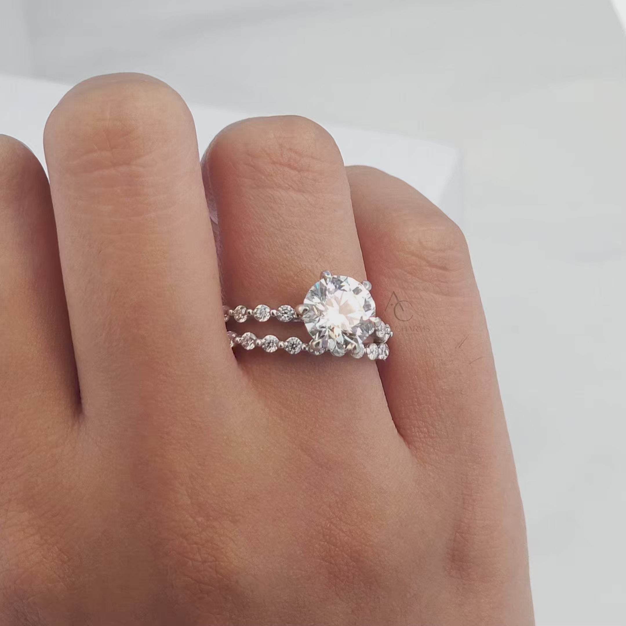 Round-cut diamond engagement ring with pave band, showcasing brilliance from angles.