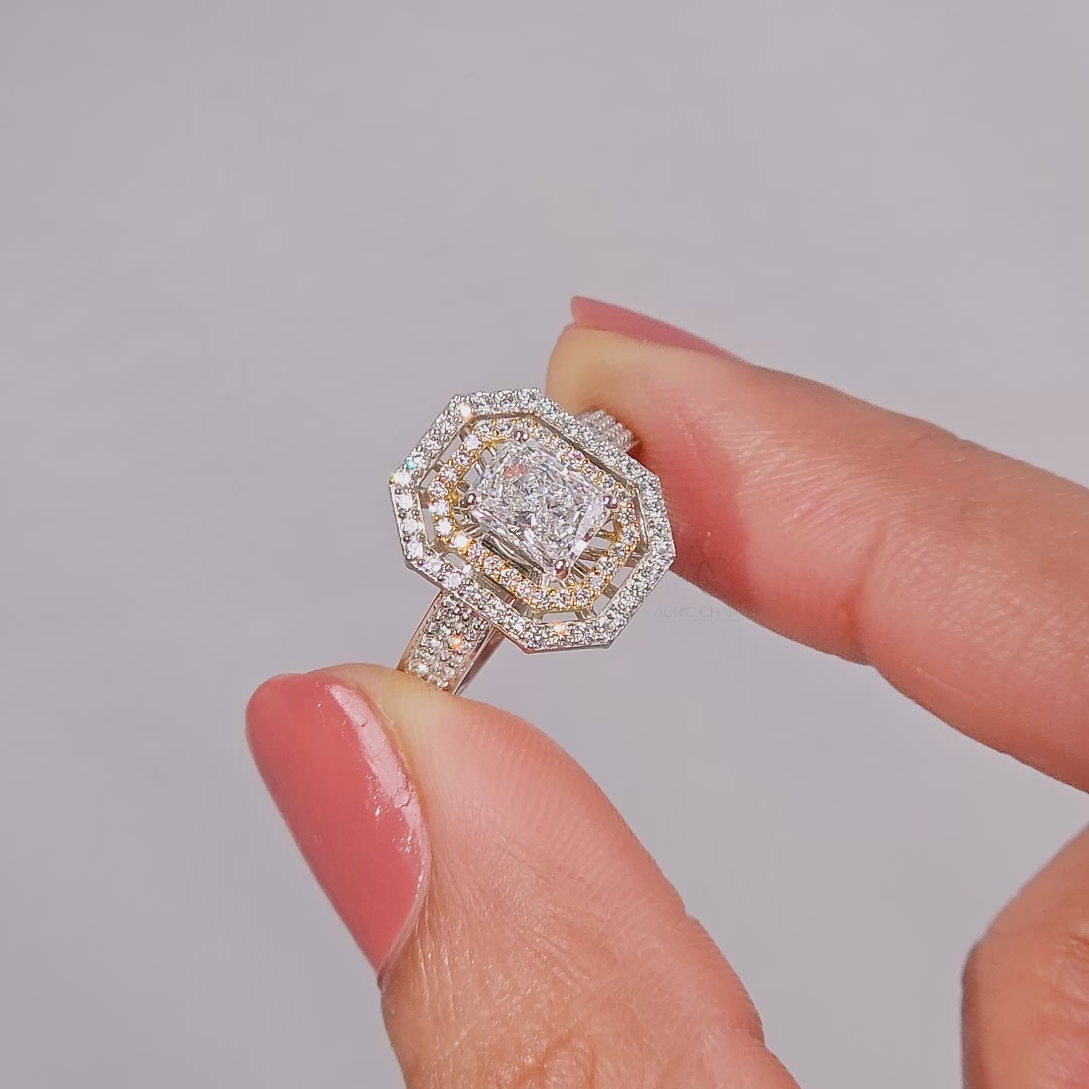 engagement ring with a rectangular Radiant-cut center stone,set on a pavé diamond band in white and yellow gold, resting on a light stone