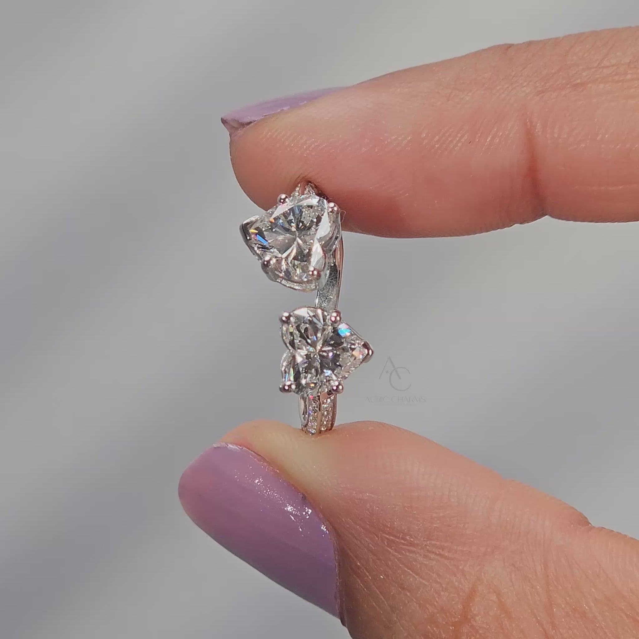 A double heart-shaped diamond ring set in silver metal.