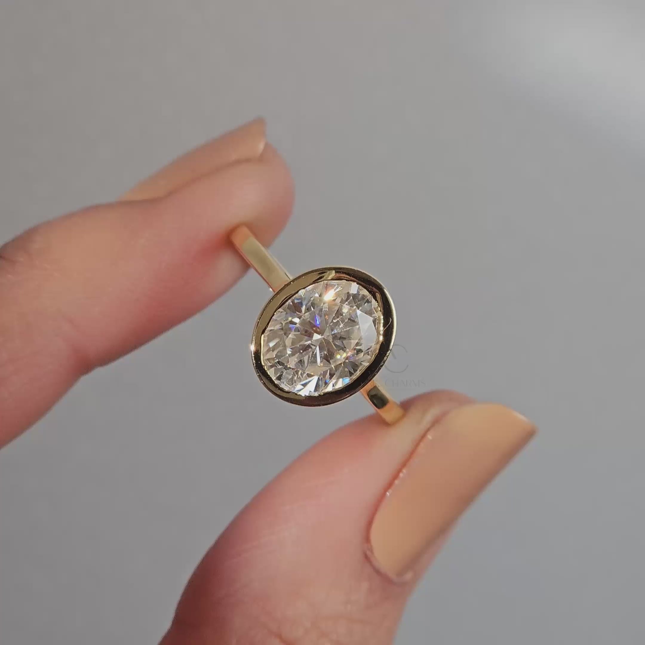 Oval solitaire diamond ring worn on hand with silver band.